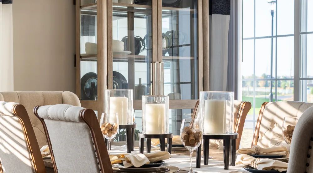 A beautifully set dining table with elegant candles and a glass cabinet in the background.