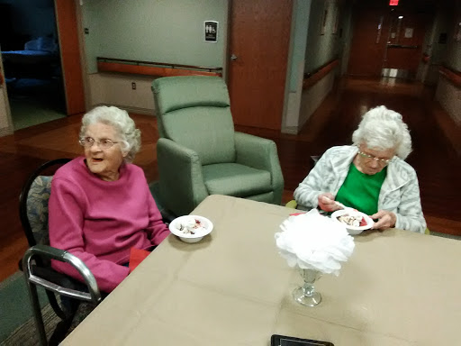 Two elderly women enjoying dessert together in a communal setting.