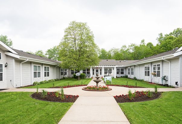 A beautifully landscaped garden with a central fountain, bordered by a modern building.