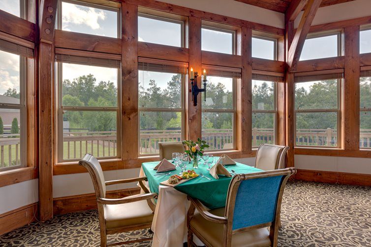 A cozy dining area with a wooden interior and large windows offering a scenic view.