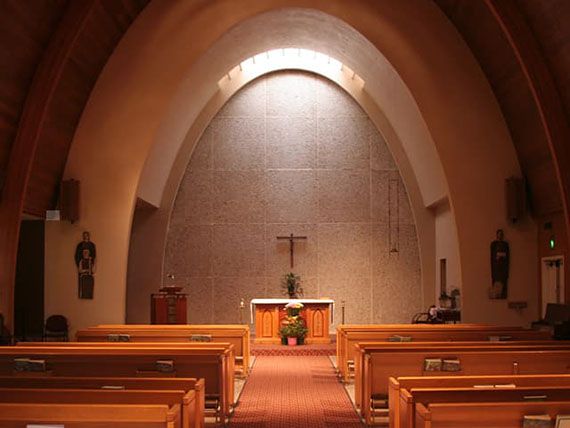 Interior view of a church with an altar and rows of pews.