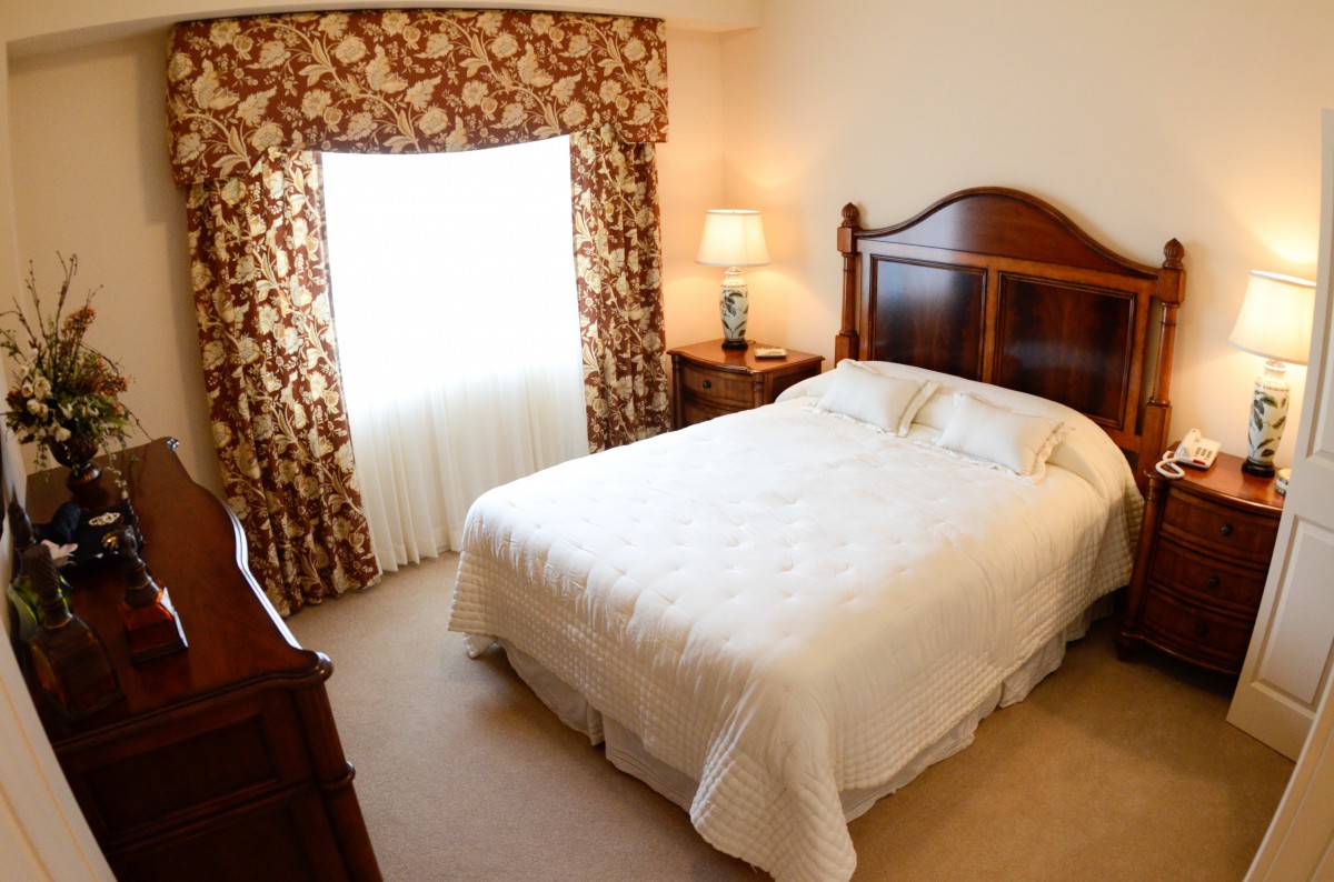 A cozy bedroom with a queen-sized bed, elegant curtains, and warm lighting.