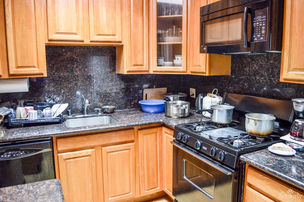 A cozy kitchen with wooden cabinets, a stove, microwave, and various appliances on the countertop.