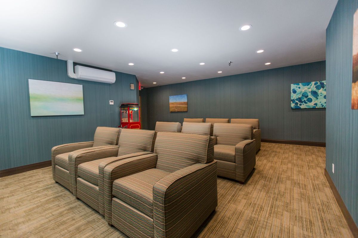 A cozy home theater with rows of recliner chairs and a projector screen.