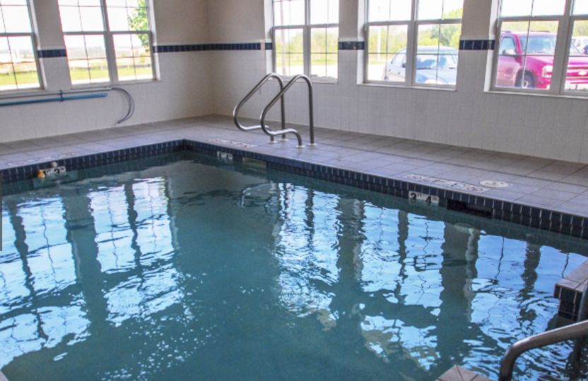 An indoor swimming pool with clear water and large windows.