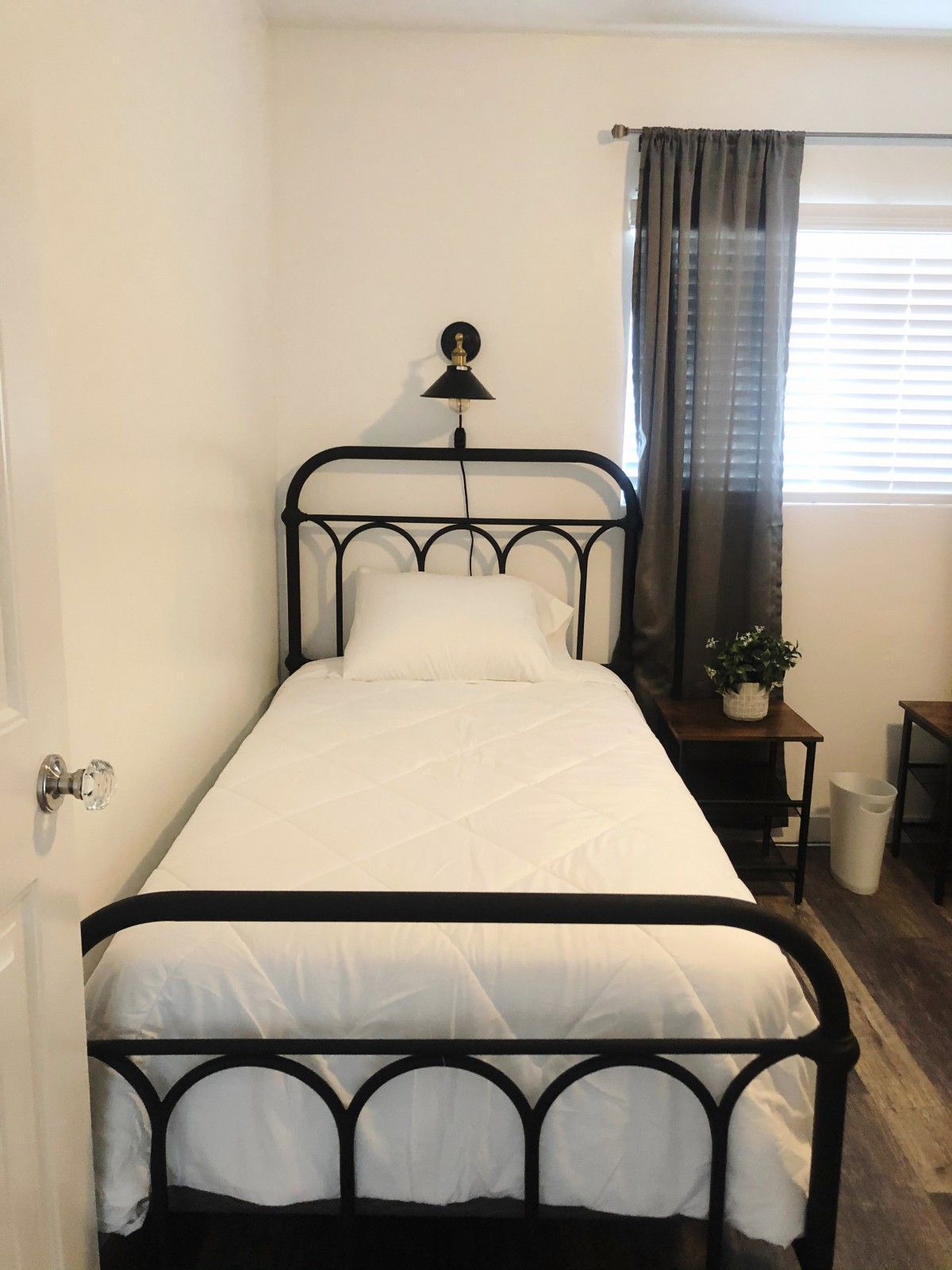 A minimalist bedroom with a single black metal-framed bed and simple decor.