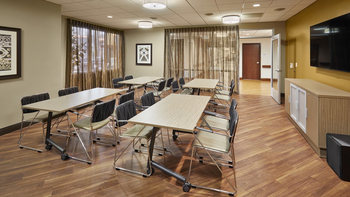 A modern conference room with neatly arranged tables and chairs, ideal for meetings or training sessions.