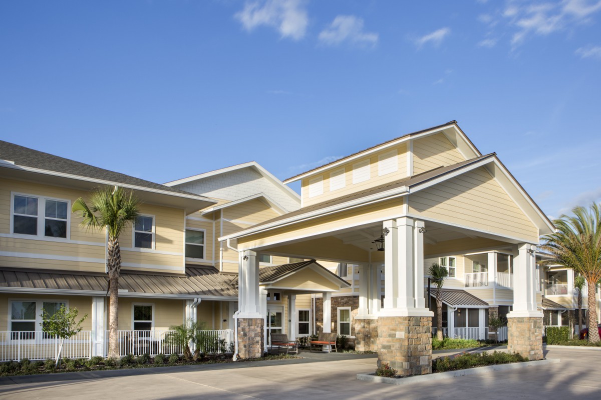 A modern residential building with a grand entrance and covered walkway.
