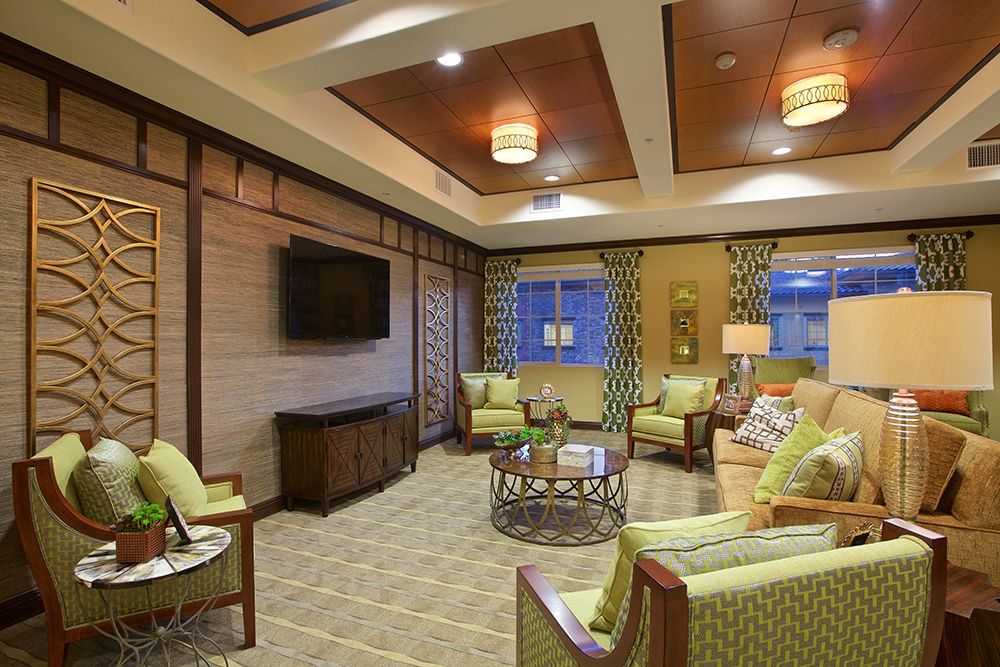 A cozy living room featuring comfortable seating and a flat-screen TV, illuminated by warm ceiling lights.