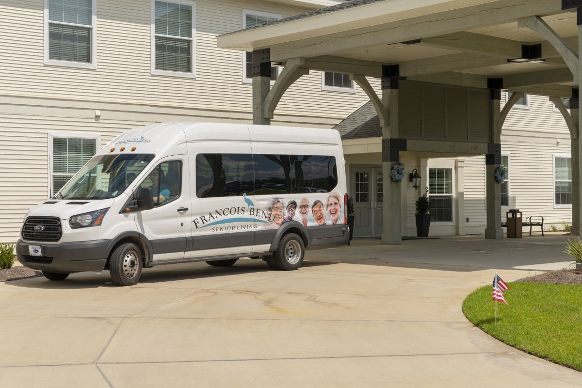 A white van parked under an awning in front of a building.
