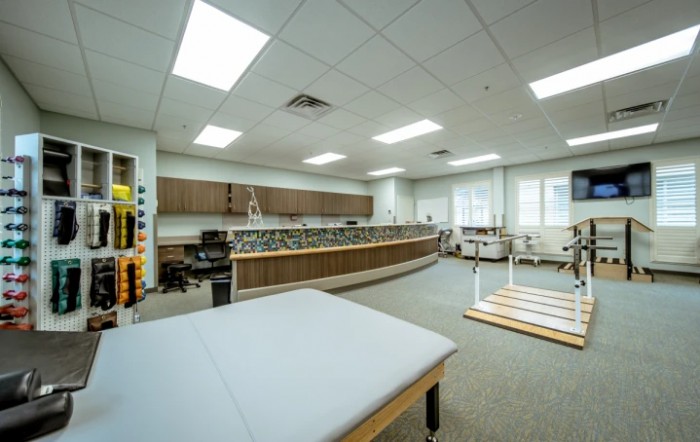 A spacious therapy room equipped with various rehabilitation tools and exercise equipment.