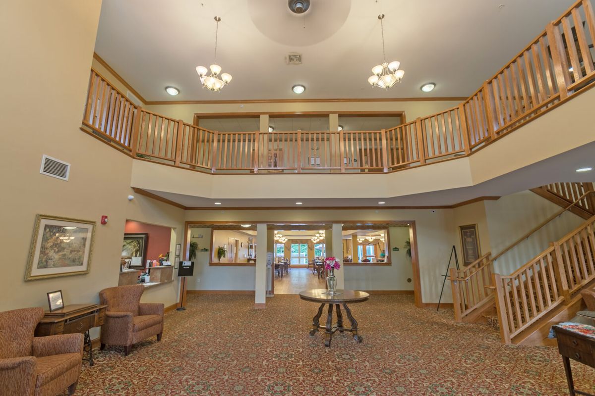 A spacious lobby area with chandeliers, wooden railings, and a central table adorned with flowers.