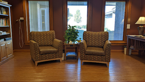 A cozy seating area featuring two patterned chairs and a small side table, complemented by a nearby plant.