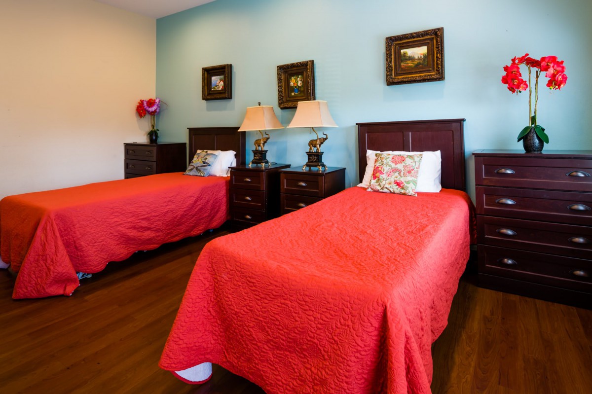 A cozy bedroom featuring twin beds with red bedding, complemented by wooden nightstands and elegant lamps.
