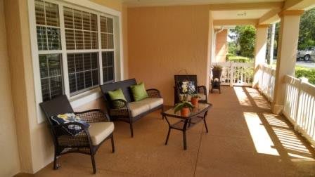 A cozy patio with outdoor furniture featuring cushions and potted plants.