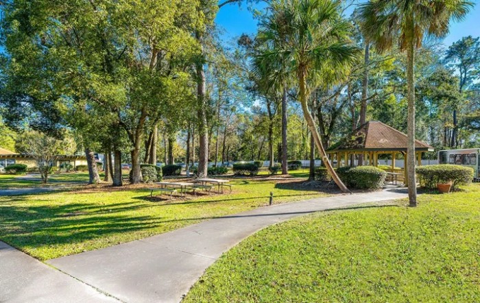 A sunny park with trees, a pathway, and a gazebo.