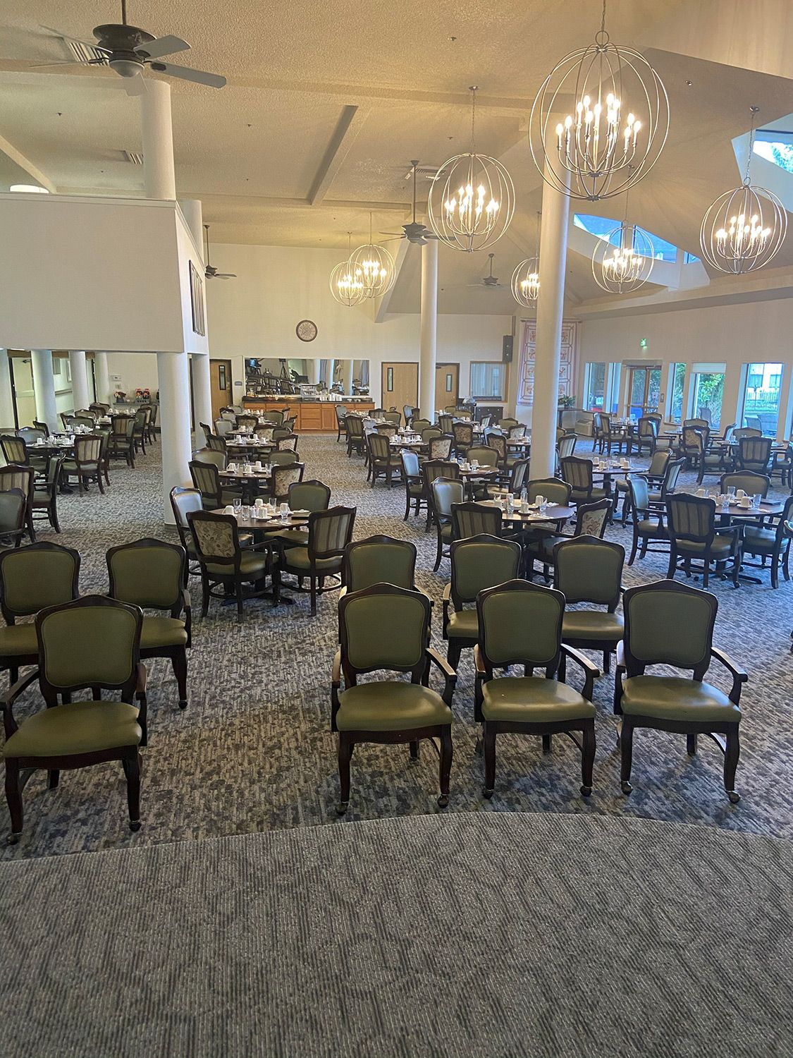 An elegant dining room with neatly arranged chairs and tables under chandeliers.
