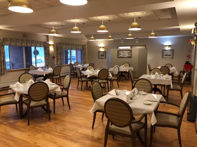 An elegant dining room with neatly arranged tables and chairs, featuring warm lighting and tasteful decor.