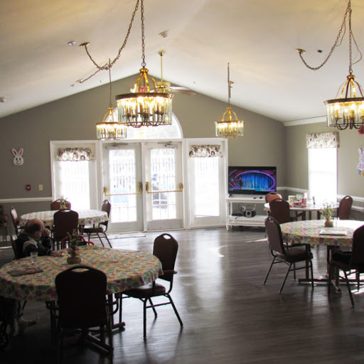 A spacious dining area featuring tables and chairs, adorned with elegant chandeliers and a large TV, perfect for gatherings.