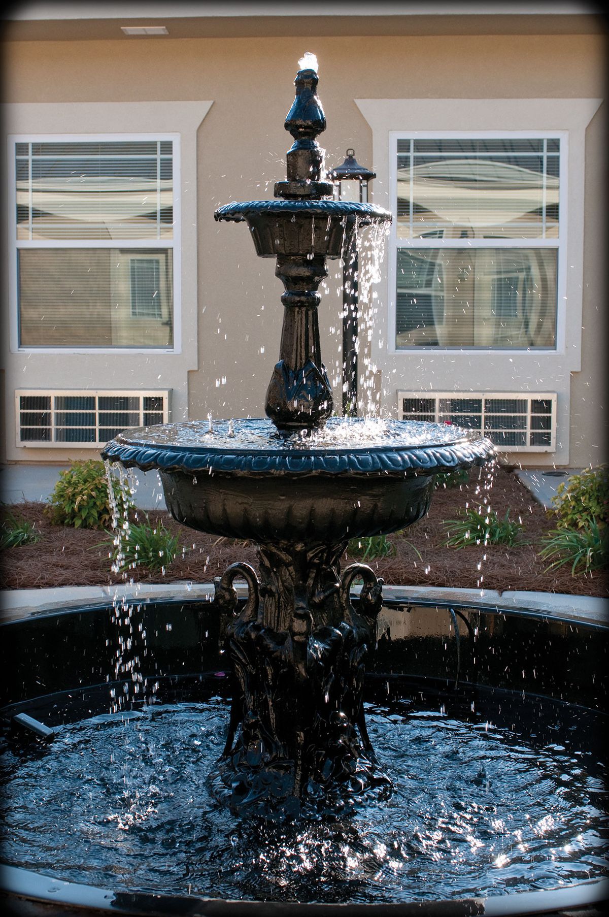 An ornamental outdoor fountain with cascading water in a garden setting.
