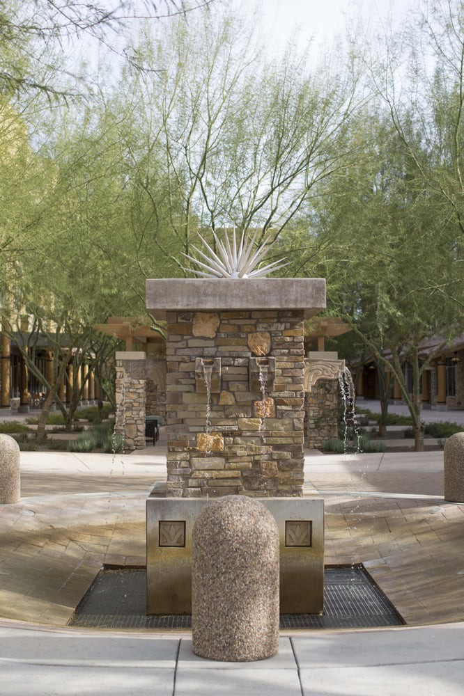 A stone fountain in an outdoor courtyard surrounded by trees.