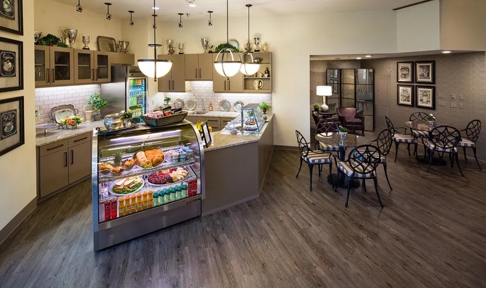 A modern kitchen and cafe area with a counter display and seating arrangements.