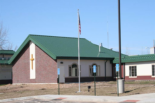 A modern church building featuring a green roof and a prominent cross.