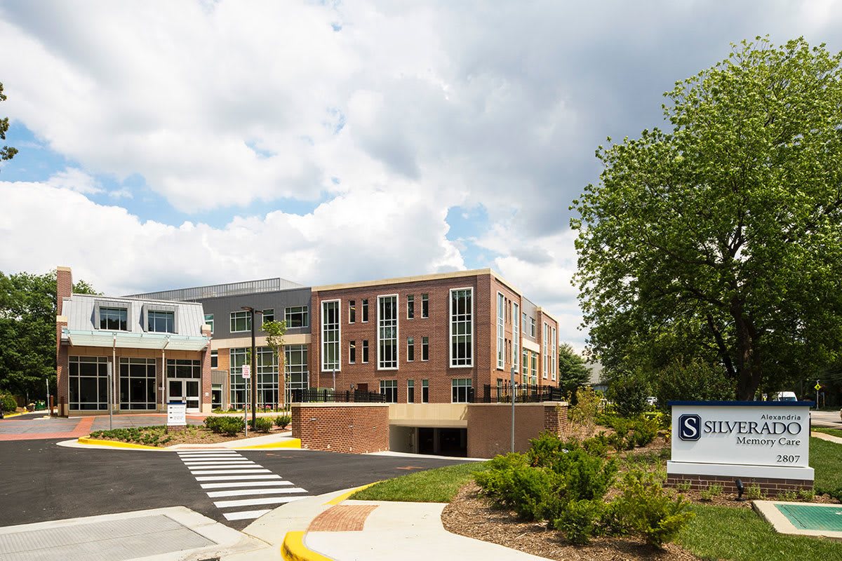 A modern school building surrounded by greenery under a cloudy sky.