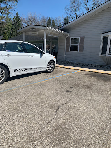 A white car parked next to a building with a wooden ramp extending towards it.