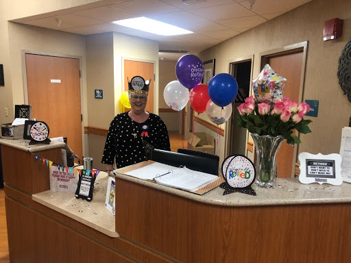 A cheerful reception area decorated for a special occasion, featuring balloons and flowers.