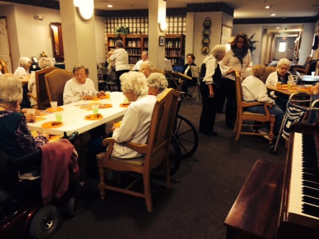 Elderly individuals enjoying a meal together in a retirement home dining area.