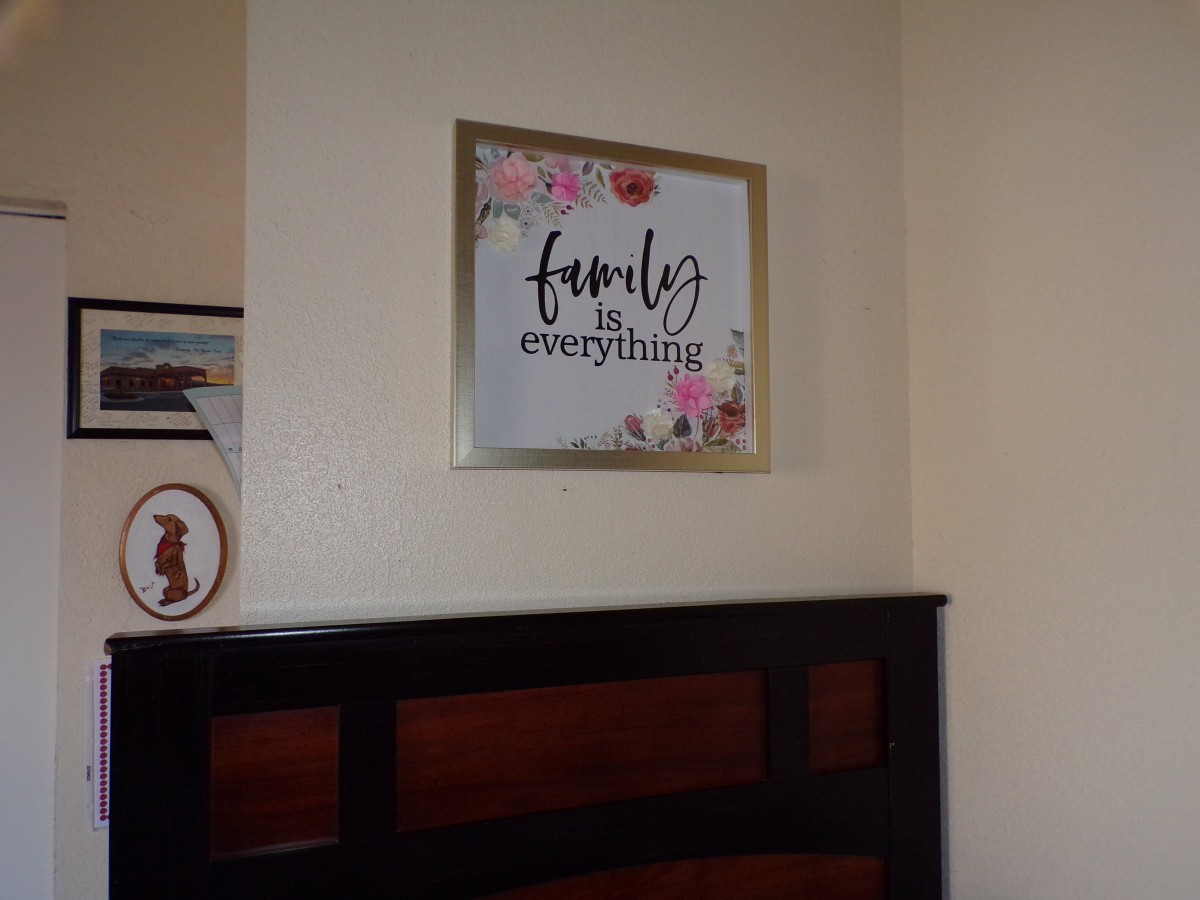 A framed wall art piece with the quote 'Family is everything' hangs above a headboard, adorned with floral designs.