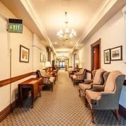 A well-lit hotel hallway with comfortable seating and elegant decor.