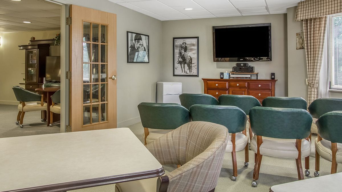 A cozy lounge area with comfortable seating, a television, and framed photographs on the wall.