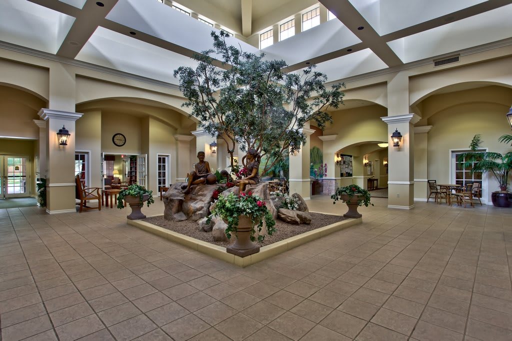 A spacious indoor atrium with a central fountain surrounded by plants, showcasing elegant architecture and interior design.