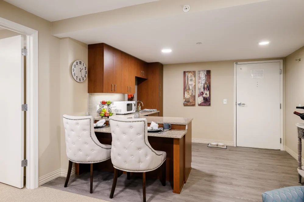 A modern kitchen and dining area featuring a wooden table with two upholstered chairs.