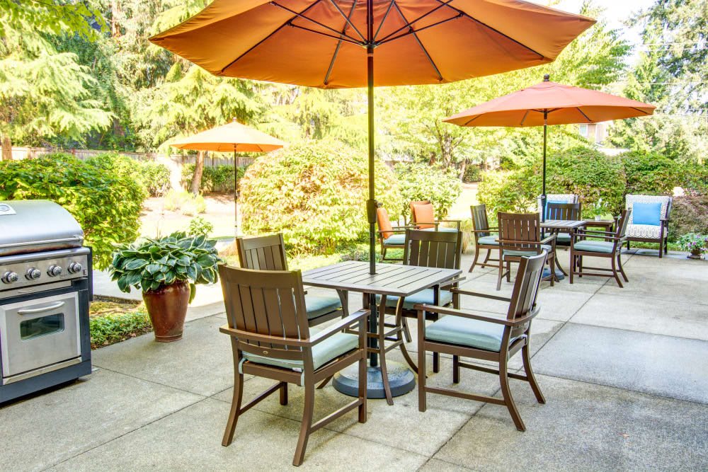 A sunny outdoor patio with tables and chairs under large orange umbrellas.