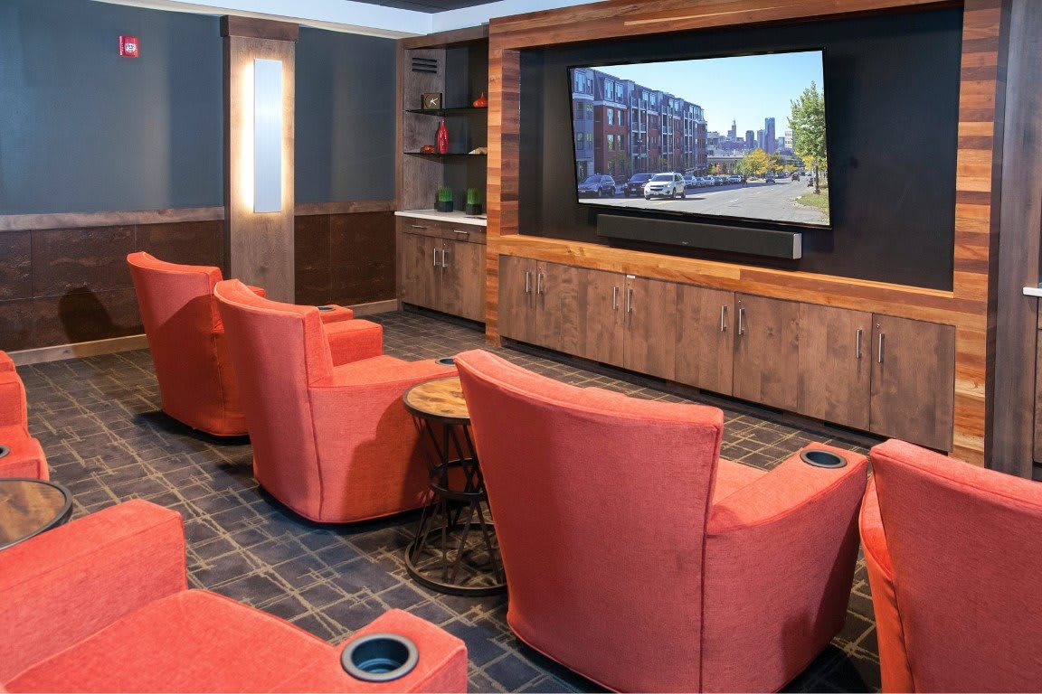 A cozy home theater room with plush red seating and a large flat screen.