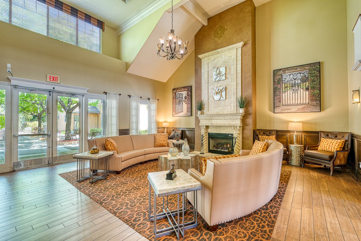 A luxurious living room featuring modern furniture, a chandelier, and a fireplace with high ceilings and large windows.