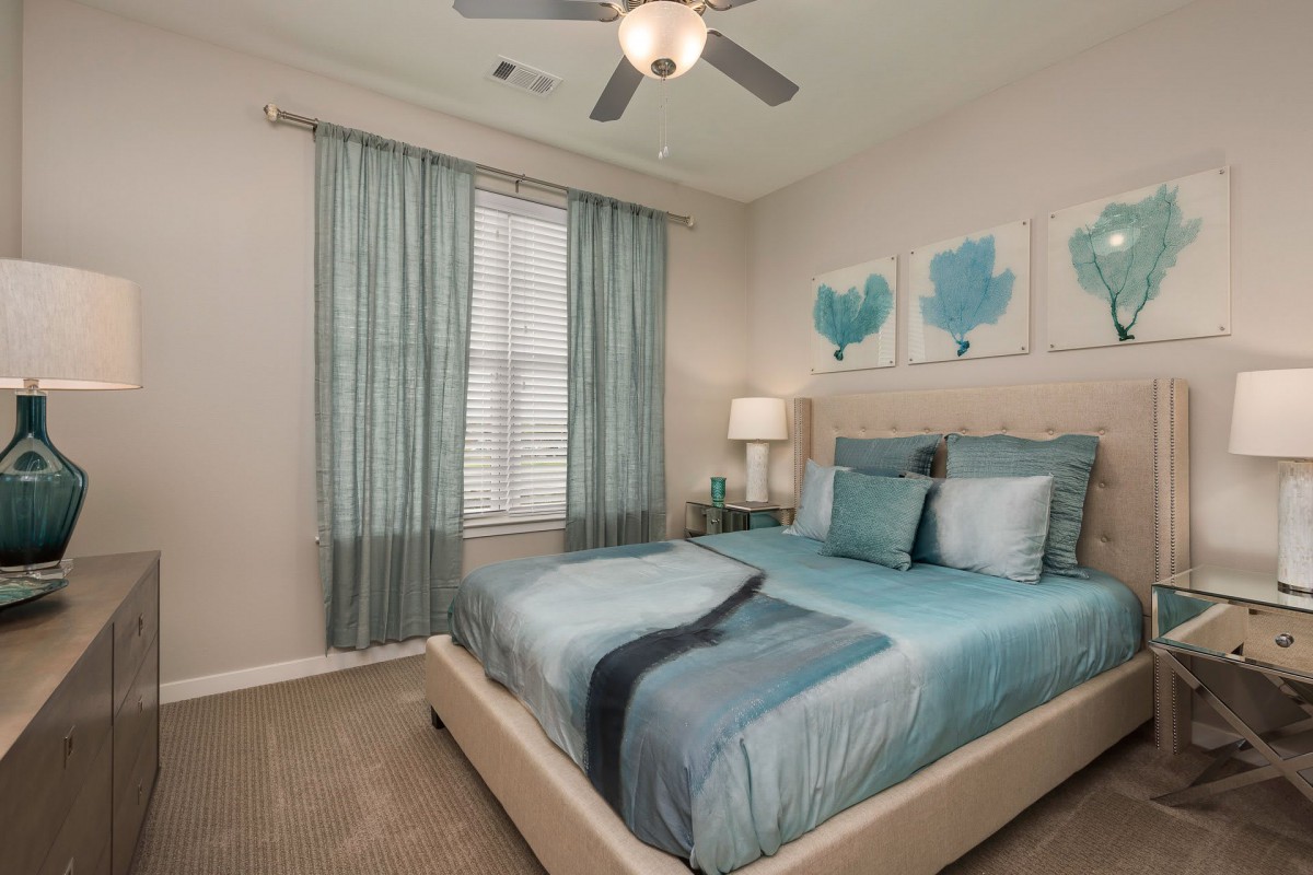 A modern bedroom with a blue color scheme, featuring stylish decor and artwork.