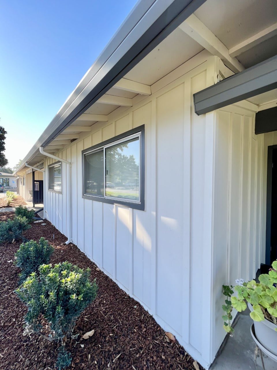 A modern white house exterior with clean landscaping and a prominent window.