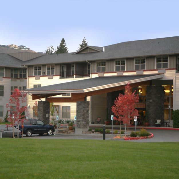 A modern building entrance with a landscaped area and parked car.
