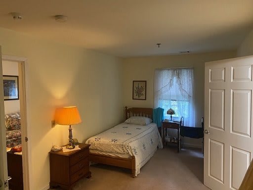 Cozy bedroom with a single bed, nightstand, and window with curtains.