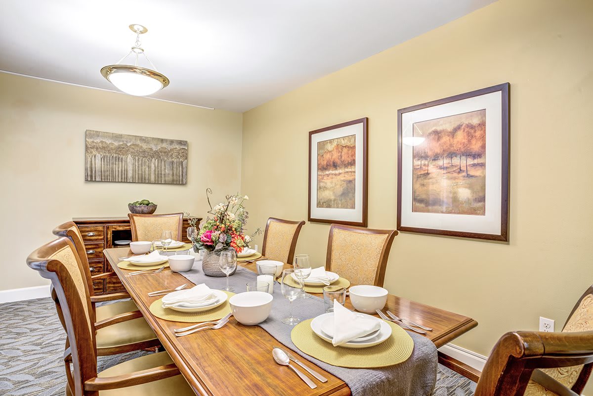 A neatly set dining room table with elegant decor and artwork on the walls.