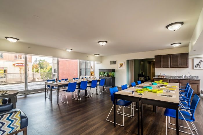 A modern, bright classroom or meeting room with blue chairs and large windows.