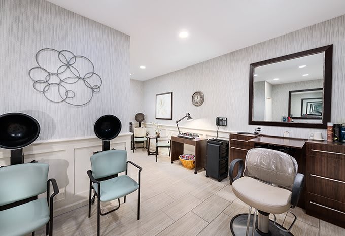 A modern salon interior featuring chairs, a large mirror, and stylish decor.