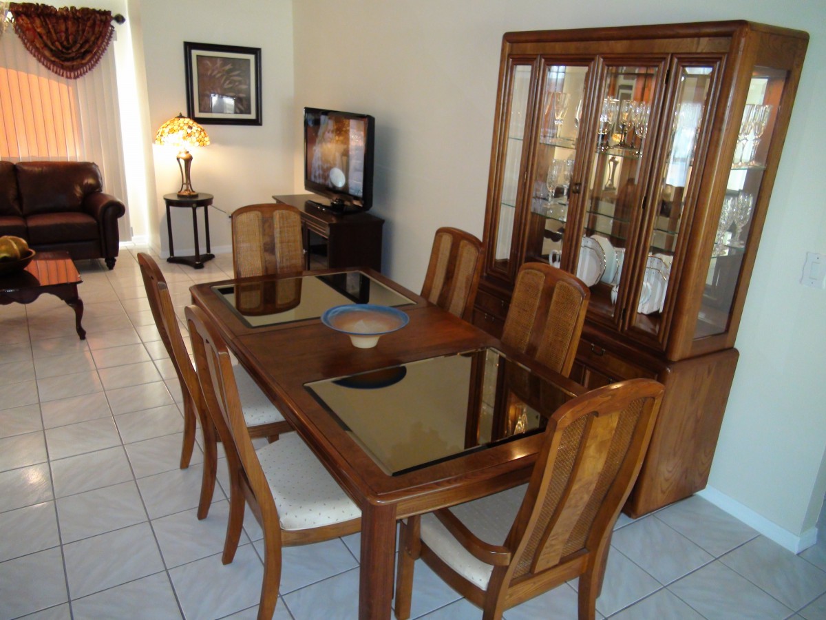 A dining room featuring a wooden dining table with six chairs and a china cabinet in the background.