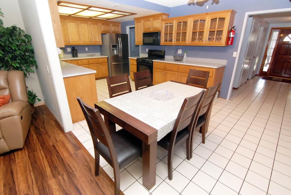 A modern kitchen with wooden cabinets, a dining table set, and various appliances.