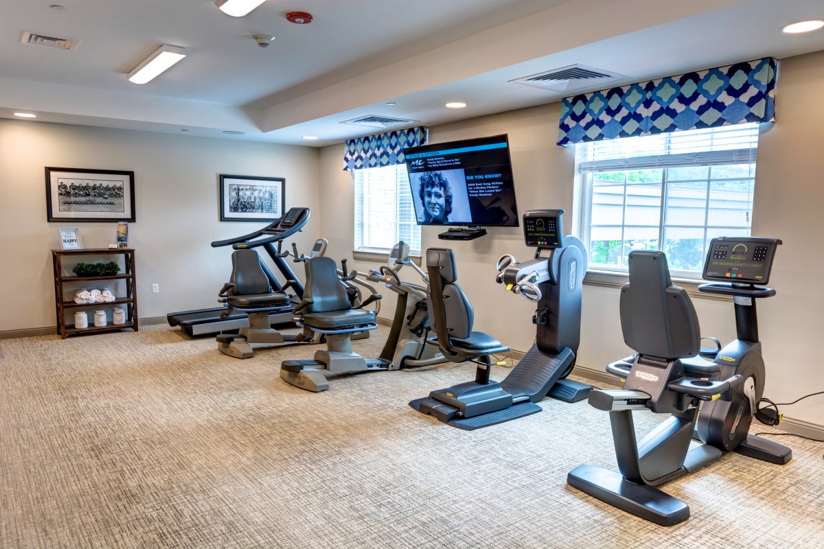 A modern fitness room with exercise machines including treadmills and stationary bikes.