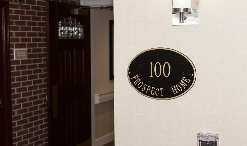 A hallway entrance with a room sign labeled '100 Prospect Home'.